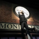 Comedian Harold Lloyd hangs from a clock in a set depicting Chaplin's film The Pawnshop.